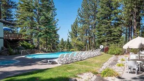 A swimming pool with lounge chairs, surrounded by tall trees and a stone pathway. - Ski Chalet with Summer Pool Access, Blocks from Heavenly  3411P~ (South Lake Tahoe)