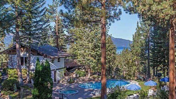 A resort with a pool area surrounded by tall trees and a mountain view. - Ski Chalet with Summer Pool Access, Blocks from Heavenly  3411P~ (South Lake Tahoe)