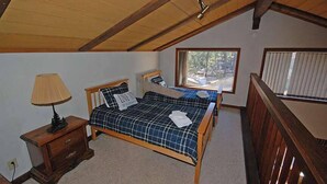 A bedroom with a wooden ceiling, a bed with a plaid bedspread, a nightstand with a lamp, and a window with blinds. - Ski Chalet with Summer Pool Access, Blocks from Heavenly  3411P~ (South Lake Tahoe)