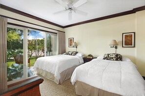 A hotel room with two beds, a ceiling fan, a large window with a view of greenery, and a small table.