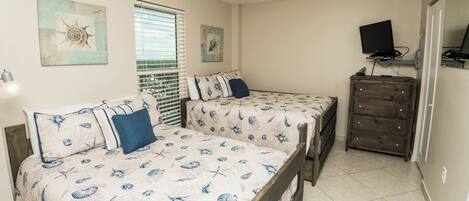 A bedroom with two beds, a dresser, a TV, and artwork on the walls.