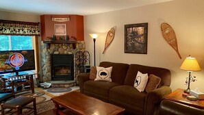 A cozy living room with a fireplace, a television, and a couch with decorative pillows. - Townhome G5 - 4th Lake (Inlet)