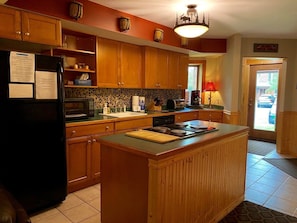 A kitchen with wooden cabinets, a black refrigerator, a microwave, and a stove.