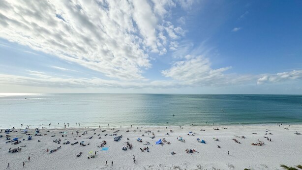 Ein Strand mit sonnenbadenden und Schwimmenden.