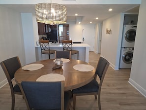 A dining area with a wooden table, chairs, and a central decorative piece. - D1006-Additional private balcony, 3 Gulf-Front pools (Panama City Beach)
