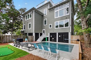 Un edificio residencial de dos plantas con piscina, zona de estar exterior y valla de madera.