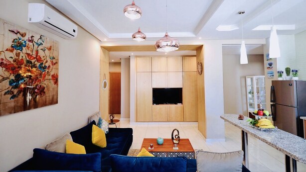 A modern living room with a blue sofa, a coffee table, and a painting on the wall. - Cozy Studio welcoming you (Casablanca)
