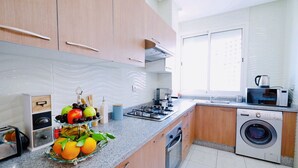 A modern kitchen with wooden cabinets, a gas stove, a microwave, and a built-in washing machine. - Cozy Studio welcoming you (Casablanca)