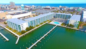 A modern hotel with a marina, featuring multiple buildings, a dock, and a view of the ocean. - Thunder Island 128C-Baywater 39th St, Free WiFi, Pool, Elev, W/D, AC (Ocean City)