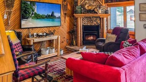 A cozy living room with a fireplace, a large TV, and a red sofa.