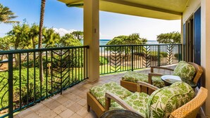 A balcony with wicker furniture, a view of the ocean, and a green railing.
