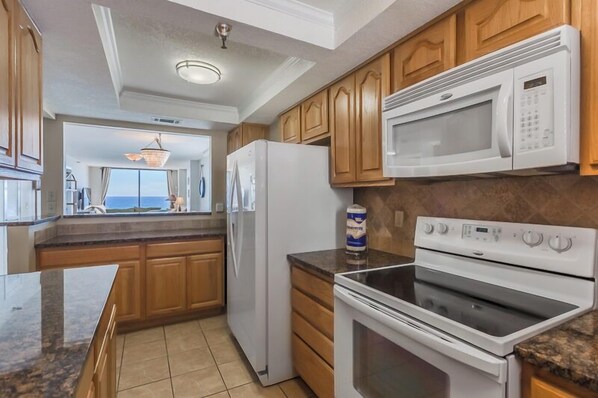 Una cocina con armarios de madera, un refrigerador blanco, un microondas y un horno.