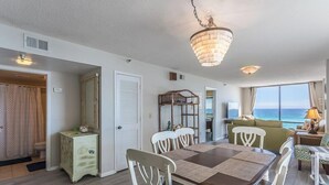 A dining area with a table and chairs, a chandelier, and a view of the ocean.