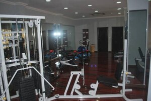 Uma academia com diversos equipamentos de exercícios, incluindo esteira e aparelhos de musculação.