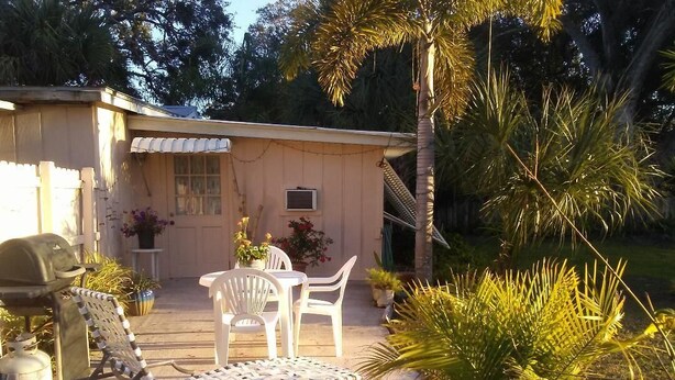 A patio area with outdoor furniture, a grill, and potted plants.