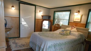 A bedroom with a bed, a nightstand, a dresser, and a window with blinds.