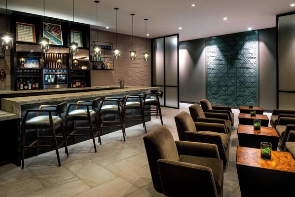 A modern bar area with a bar counter, seating, and ambient lighting. - AC Hotel by Marriott Boston Cleveland Circle (Boston)