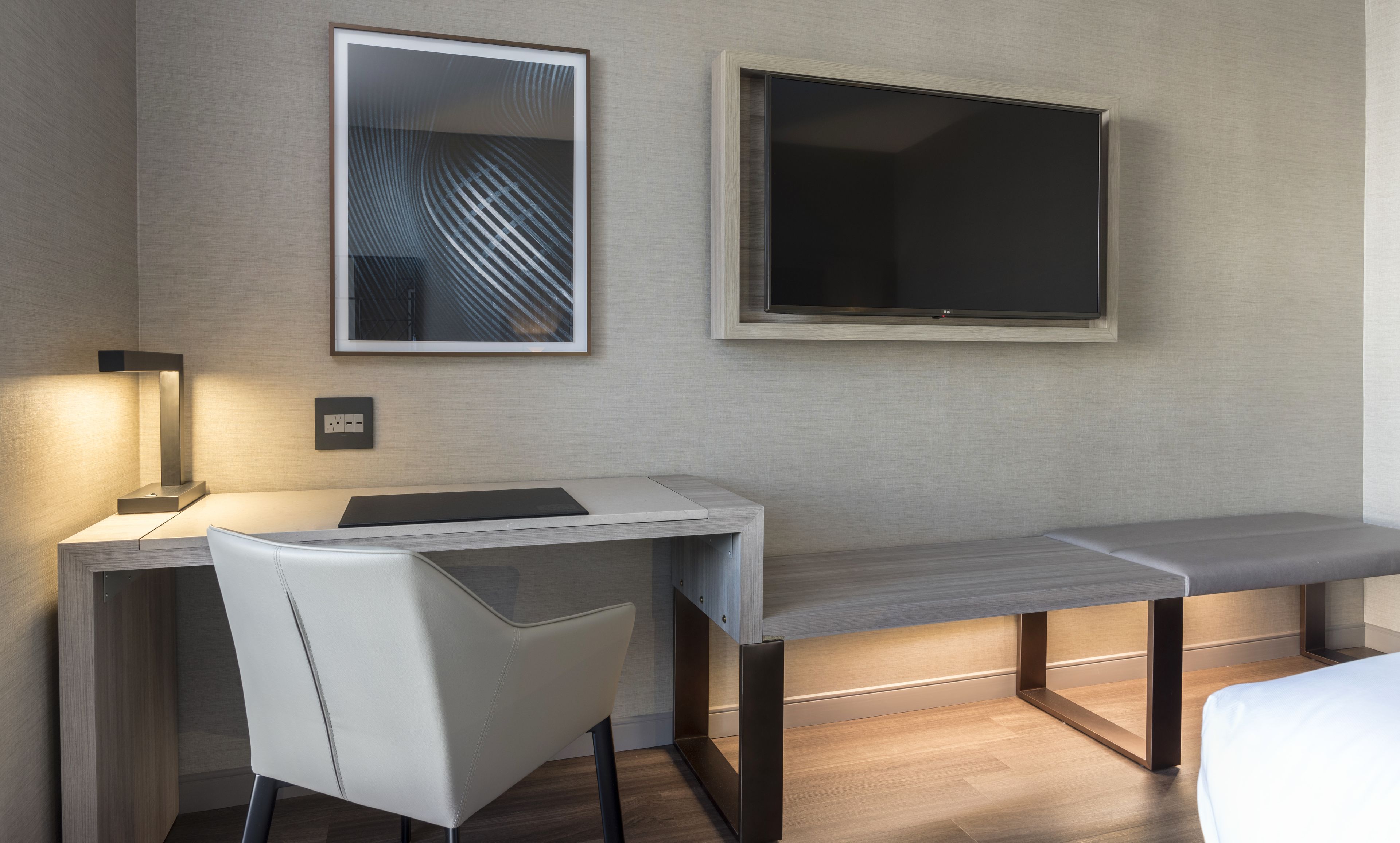 A modern hotel room with a desk, chair, and a large window.