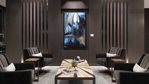 A modern room with a central coffee table, two armchairs, and a large abstract painting on the wall. - AC Hotel by Marriott Boston Cleveland Circle (Boston)