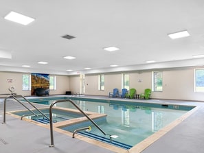 An indoor swimming pool with a clear water surface, surrounded by a tiled deck.
