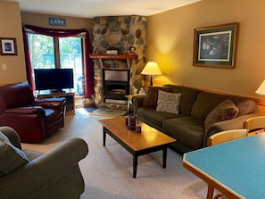 A cozy living room with a stone fireplace, a television, and a comfortable seating area.