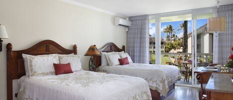 A hotel room with two beds, a balcony with a view of palm trees, and a dining area.