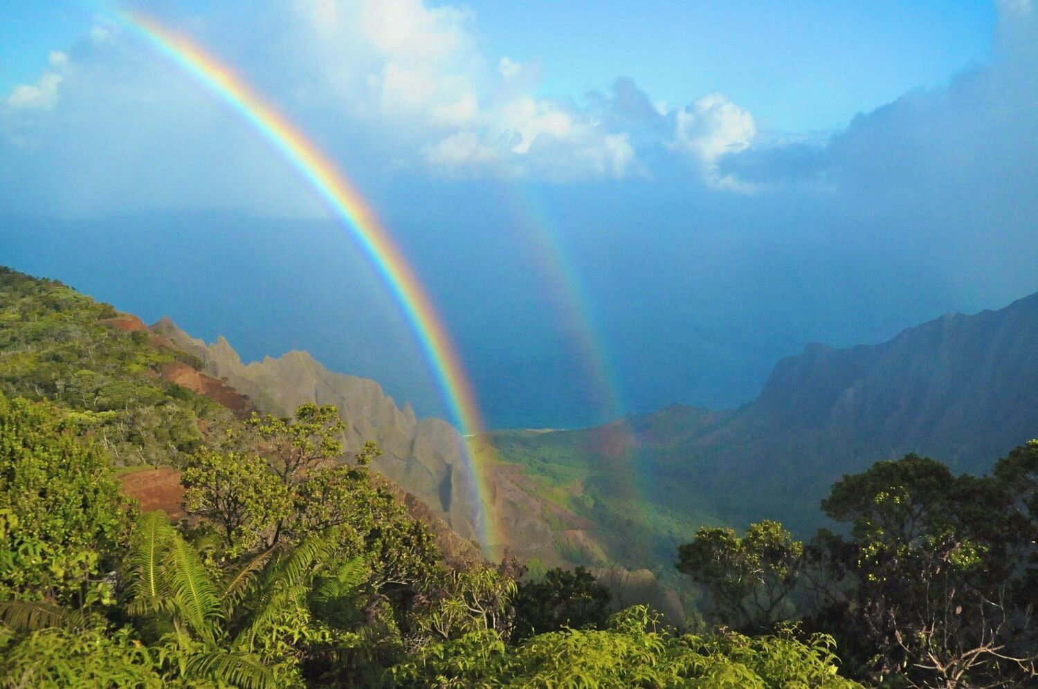 A landscape with a double rainbow over a mountainous area.
