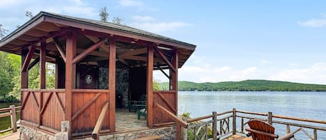 A wooden cabin with a porch, a chair, and a view of a lake.