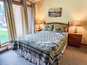 A bedroom with a large bed, two bedside tables with lamps, a window with curtains, and a welcome sign on the wall.