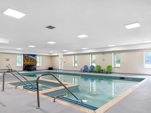 An indoor swimming pool with a clear water surface, surrounded by a tiled deck.