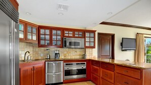 Una cocina moderna con armarios de madera, electrodomésticos de acero inoxidable y salpicadero de azulejos.