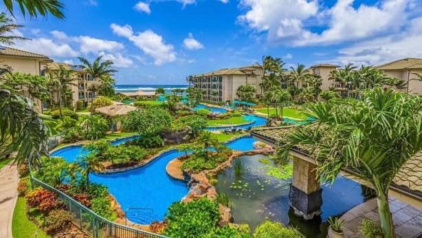Un resort con varias piscinas, palmeras y vistas al océano.