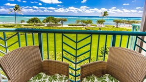 A balcony with wicker chairs and a view of the ocean.