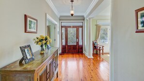 A hallway with wooden flooring, a wooden bench, a vase with flowers, and framed pictures on the wall. - 7 41st Avenue by AvantStay | Private Pool, Near Beach (Isle of Palms)