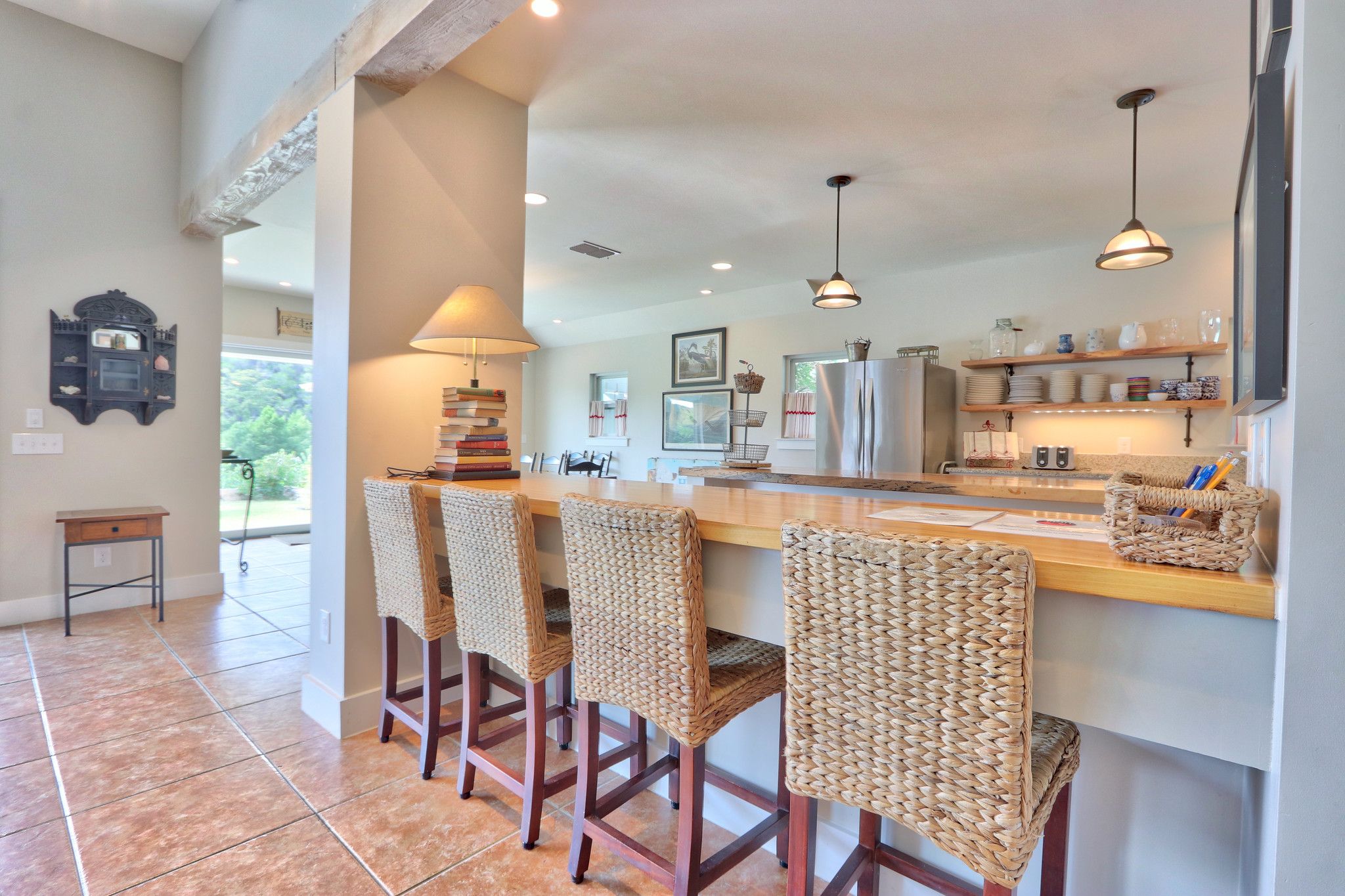A kitchen with a central island, bar stools, and a hanging light fixture.
