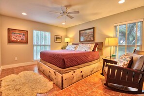A bedroom with a wooden bed, a chair, a rug, and two windows. - Relaxation awaits you. Open spaces throughout! The Blanco River welcomes you. (Wimberley)
