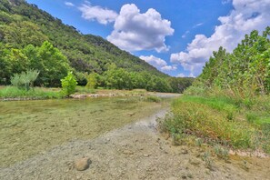 Un río transparente con rocas visibles y vegetación en las orillas.