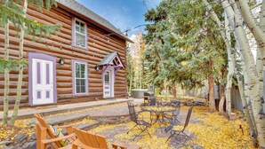 A log cabin with a patio area featuring outdoor seating and a stone fireplace. - Walk to Ski Shuttle! Breckenridge Cabin w/ Hot Tub (Breckenridge)