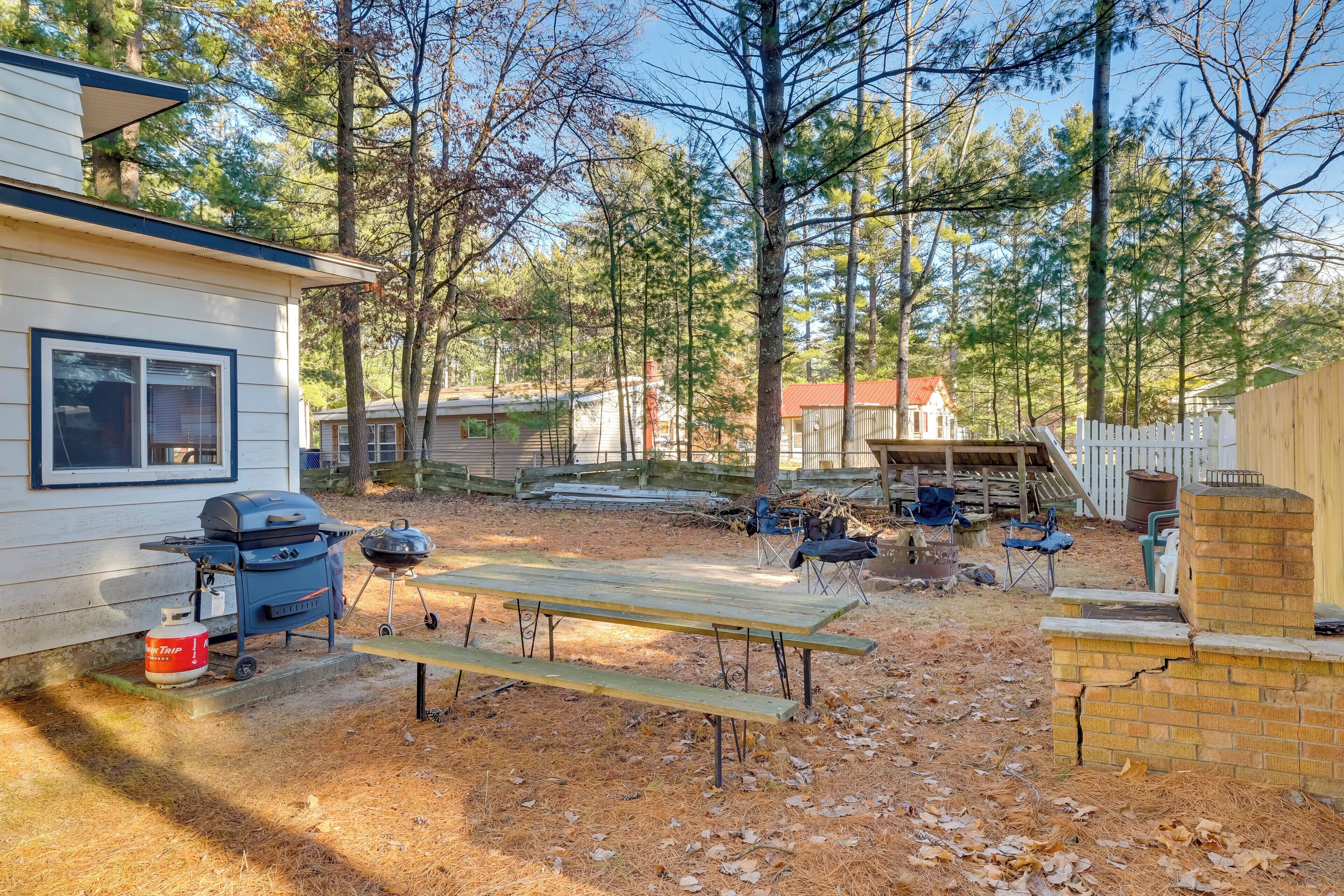 Ein Garten mit Grill, Picknicktisch und einer Holzterrasse.