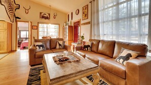 A spacious living room with leather sofas, a coffee table, and a large window. - Wisconsin Cabin w/ ATV Trails, Near Lake Arbutus! (Hatfield)