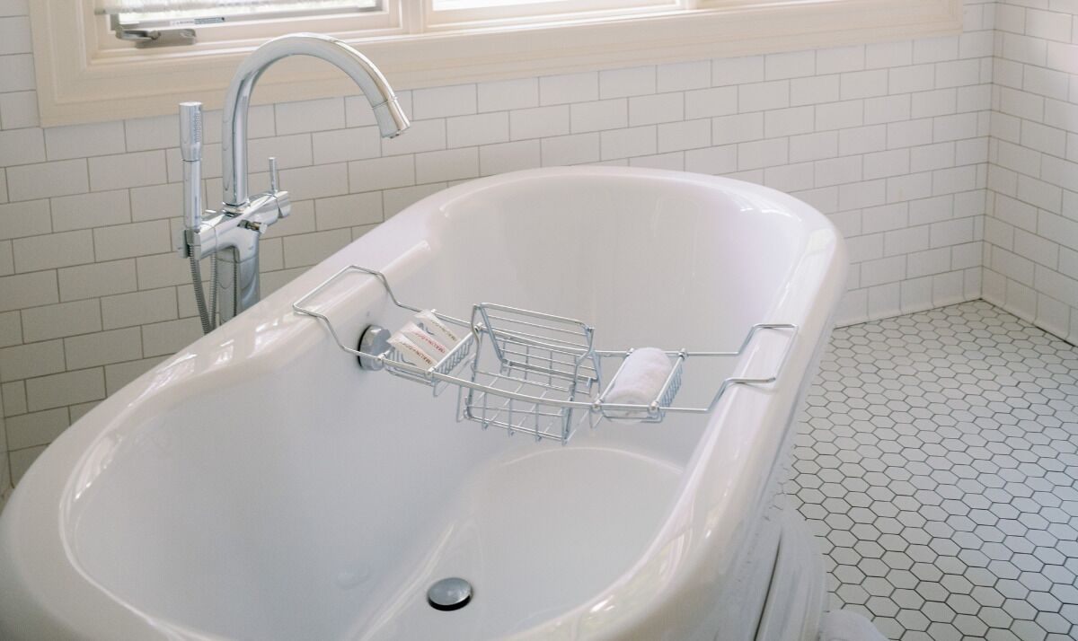 A bathroom with a white bathtub, a shower, and a tiled floor.