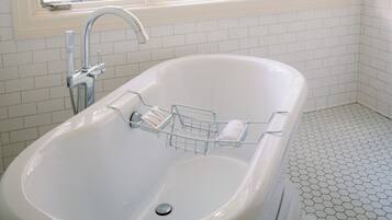 A bathroom with a white bathtub, a shower, and a tiled floor.