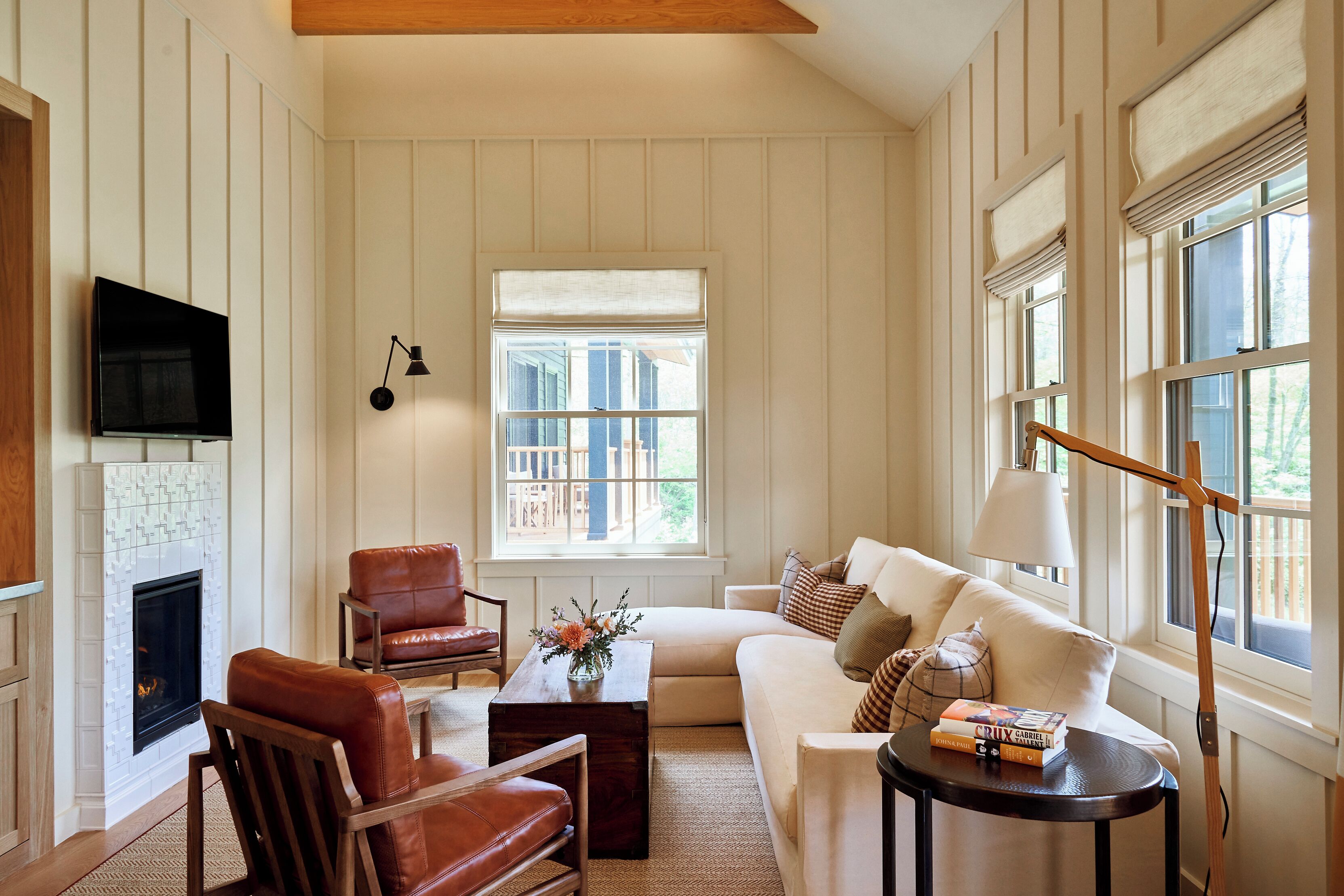A living room with a fireplace, leather chairs, a sofa, a coffee table, and a TV mounted on the wall.
