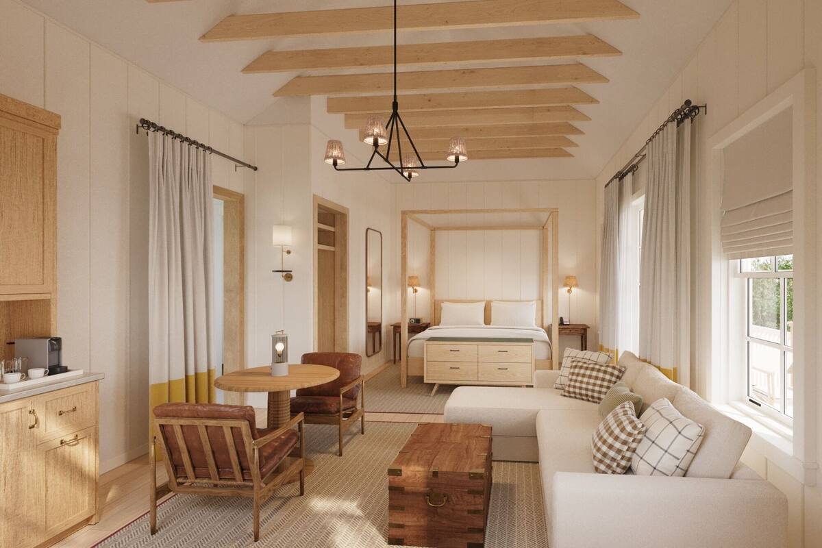 Une chambre d’hôtel spacieuse avec un grand lit, un coin salon avec un canapé et des fauteuils, une table à manger et un coin cuisine équipé de placards et d’une machine à café.