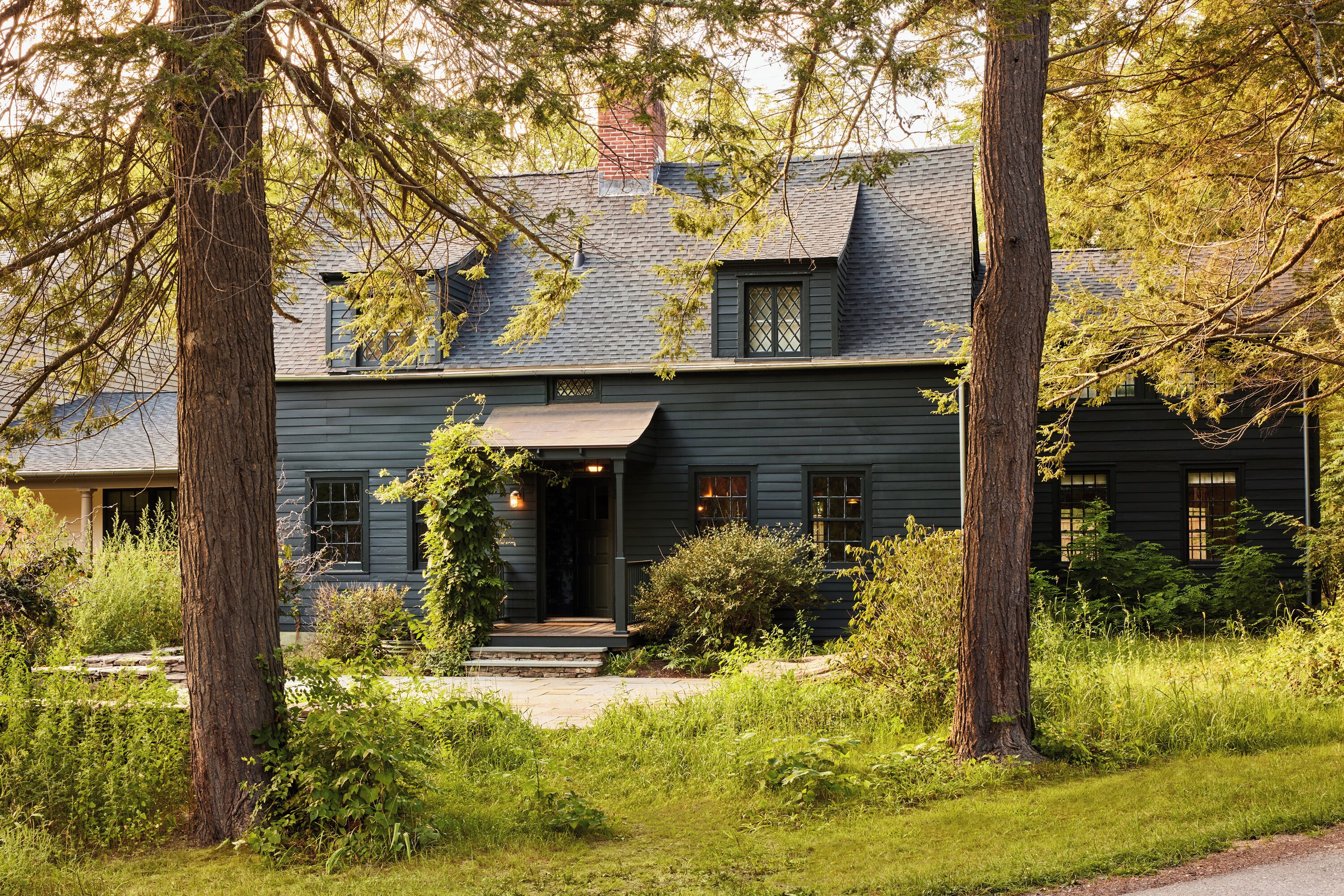 A two-story house with a dark exterior, a front porch, and a chimney.