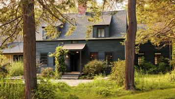 A two-story house with a dark exterior, a front porch, and a chimney.