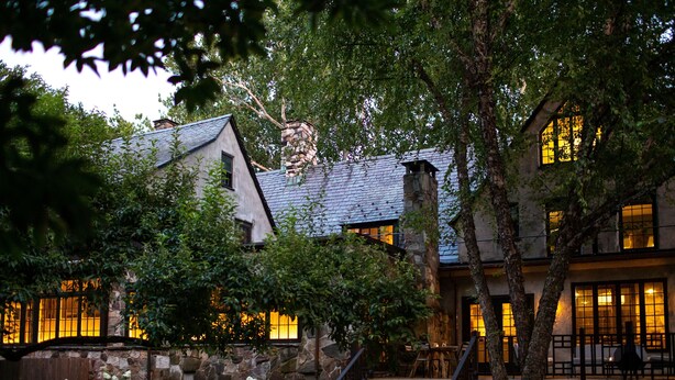A stone building with a wooden staircase and a garden with white flowers. - Troutbeck (Amenia)