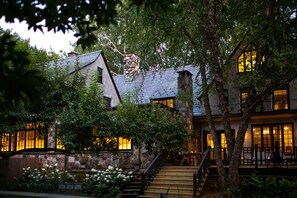 A stone building with a wooden staircase and a garden with white flowers. - Troutbeck (Amenia)