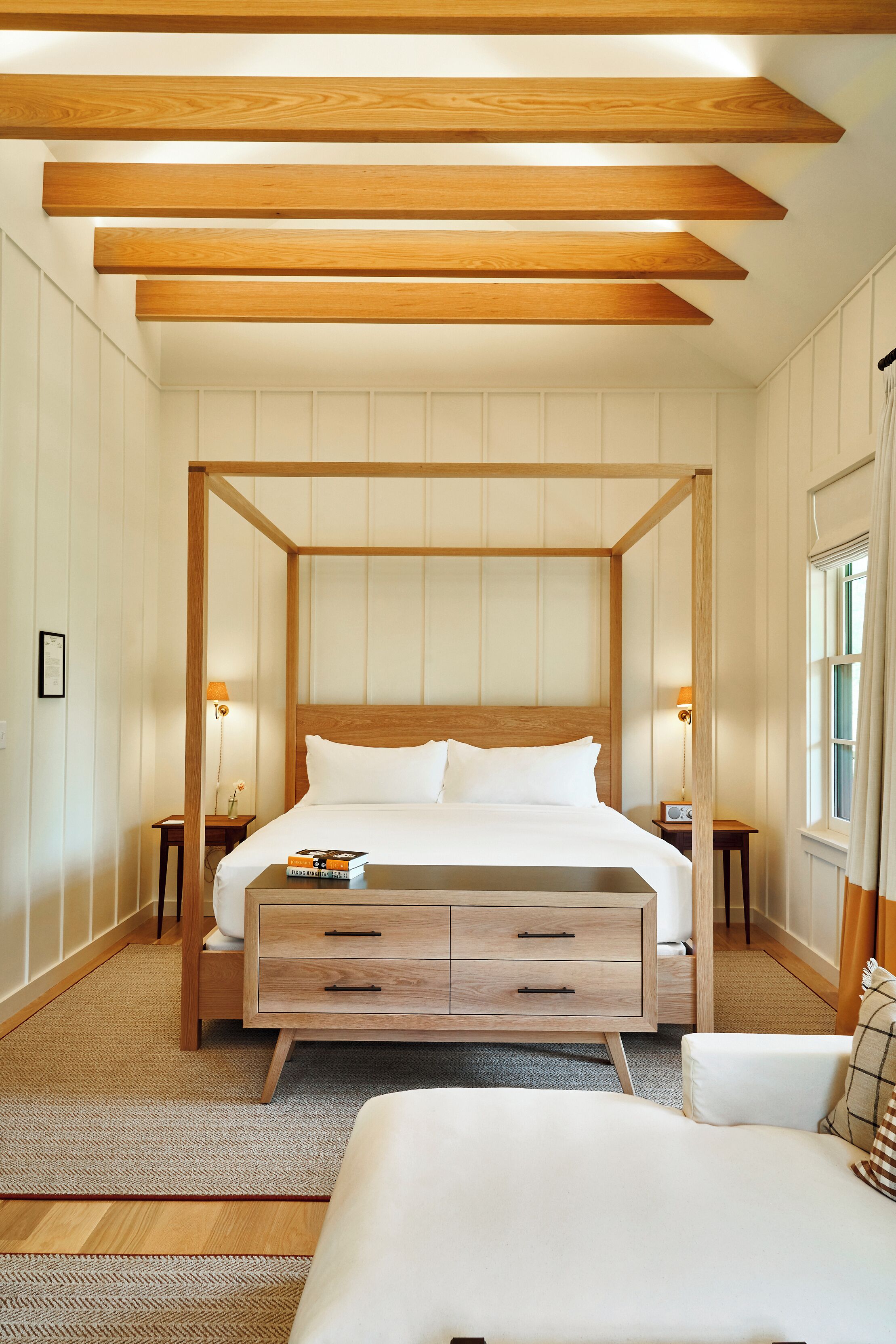 A four-poster bed with a wooden frame, bedside tables, and a bedside lamp.