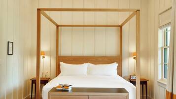 A four-poster bed with a wooden frame, bedside tables, and a bedside lamp.